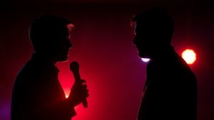 Două siluete confruntându-se în fața luminii.